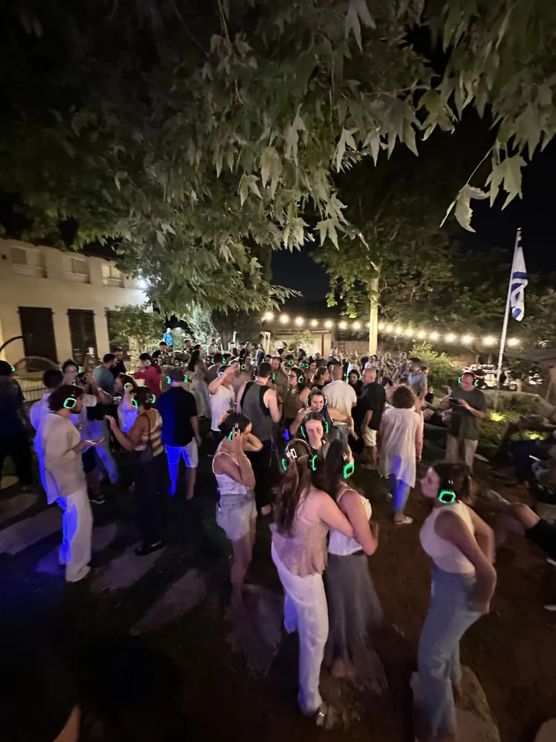 קהל גדול רוקד בגינה עם אוזניות ירוקות